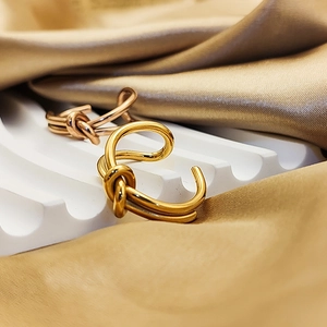 Detailed view of minimalist knot design rings in gold and rose gold on silk