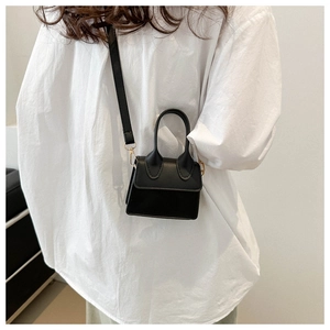 Mini schwarze Umhängetasche an einem Model in weißem Hemd in minimalistischem Stil