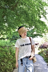 Outdoor summer outfit featuring a raffia straw visor and white graphic t-shirt in nature