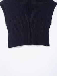 Gros plan détaillé de la texture en maille côtelée et couture diagonale sur le gilet bleu marine