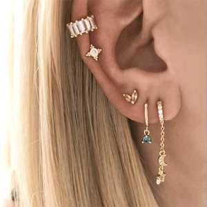 Detail view of gold star moon earrings and zircon ear cuffs on a female model