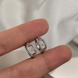 Detail of silver pig nose huggie earrings with micro-set zircons held by hand