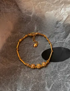 Detail of 18K gold-plated bamboo joint bracelet with carved beads on dark gray art paper
