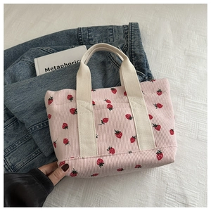 Detail of pink corduroy handbag with strawberry print on denim jacket background