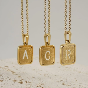 Détail des pendentifs carrés plaqués or 18 carats avec les lettres A, C et R