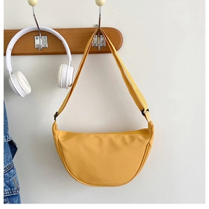 Vue détaillée d'un joli sac bandoulière croissant en nylon jaune accroché au crochet.
