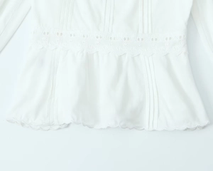 Vue détaillée de la blouse brodée blanche avec bordure en dentelle et ourlet plissé