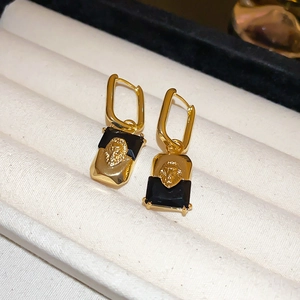 Detail of vintage gold-plated lion head earrings with black rectangle gemstones