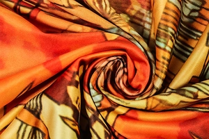 Close-up of retro printed fabric with vibrant orange and yellow patterns and silky texture
