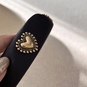 Macro view of a black satin headband featuring a vintage gold heart metal embellishment
