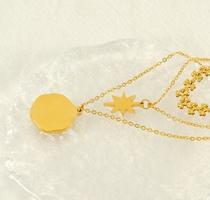 Detail view of gold multi-layer necklace with star pendant on ice decor