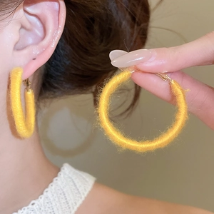 Detailed view of yellow flocked hoop earrings on a model for autumn winter style