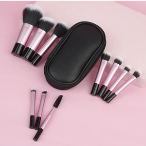 Close-up of 10-piece mini makeup brush set with pink handles and black travel zipper pouch