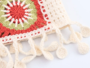 Detail of bohemian crochet cardigan showing red and green geometric floral knit patterns