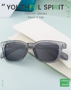 Detail of matte gray semi-transparent sunglasses with gold arrow metal accents on white case