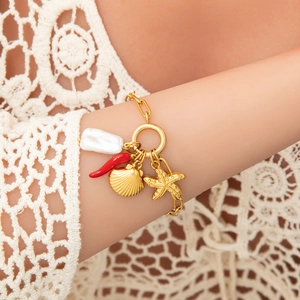 Golden charm bracelet with baroque pearl, red chili, and starfish on lace background