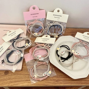 Detail of high-elasticity hair ties with pink and cream beads on wooden background