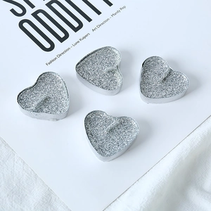 Detail of four heart-shaped candles with silver glitter surface on a minimalist background
