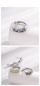 Macro shot of silver hoop earrings with three colorful inlaid zircons and hinged clasp
