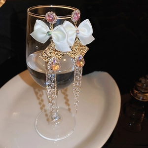 Detail of pink crystal butterfly tassel earrings hanging on a crystal wine glass