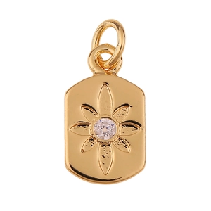 Detalle de un colgante de escudo dorado con flor grabada y piedra preciosa brillante