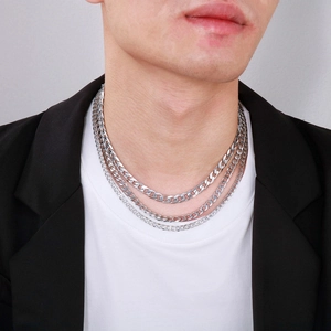 Close-up of triple layered silver Cuban chain necklaces worn with a black suit