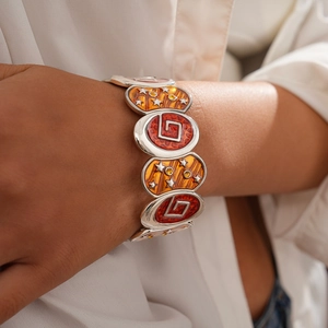 Detailed view of bohemian stretch bracelet with red enamel stars and geometric motifs