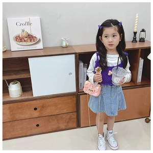 Girl wearing purple knitted vest and denim skirt with pink quilted crossbody bag