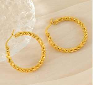 Gros plan de boucles d'oreilles créoles torsadées en acier doré au design texturé
