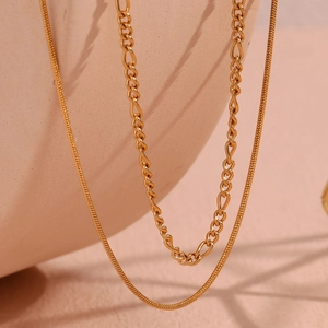 Detailed macro of 18K gold plated double layer Figaro and flat snake chain necklace