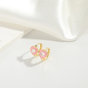 Elegant gold heart earrings with pink enamel and sparkling zircon on white silk background