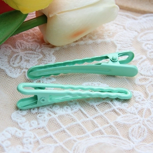 Pair of mint green seamless wave and straight metal hair clips on white lace background