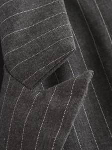 Macro shot of dark grey pinstripe fabric texture and stitching on suit lapel
