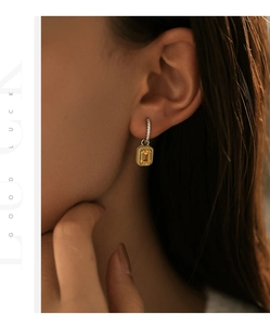 Dettaglio elegante orecchino in argento s925 con gemma gialla indossato da modella