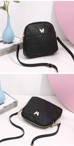 Detail of black quilted crossbody bag featuring golden butterfly hardware and leather strap