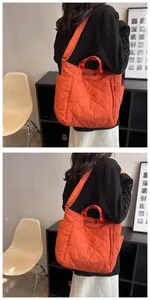 Detailed view of an orange quilted tote bag featuring large diamond stitching and wide straps