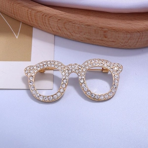 Macro shot of cute glasses-shaped brooch with sparkling rhinestones and gold alloy base