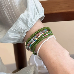 Detail of bohemian seven-piece colorful seed bead bracelets on model wrist