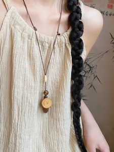 Close-up of wood slice and acorn pendant on long adjustable necklace cord