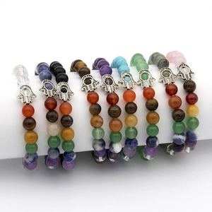 Detail of colorful chakra bead bracelets with metallic Hamsa Hand charms on white background