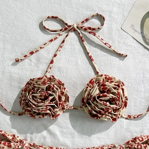 Detailed close-up of 3D fabric rose flower on a halter bikini top with red floral print