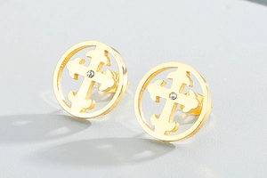 Detailed macro shot of golden hollow cross stud earrings with sparkling crystal centers