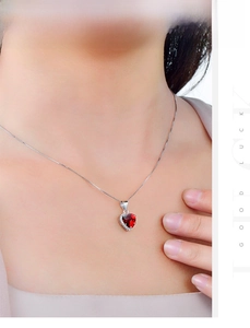 Detail of s925 silver necklace featuring a heart-shaped red zircon pendant with halo stones