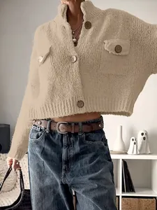 Detail of chunky knit cropped cardigan featuring tortoiseshell buttons and flap pockets