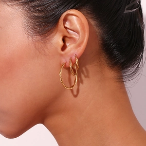 Detailed view of three 18K gold plated twisted hoop earrings worn in a stack on ear