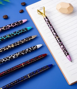 Close-up of leopard print metal ballpoint pens with large crystals on a notebook
