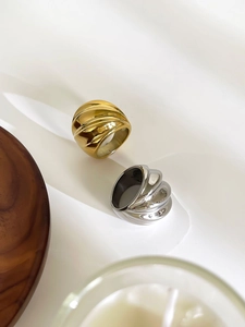 Gros plan d'une bague texturée en or 18 carats et argent sur fond de tissu blanc
