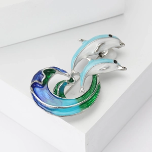 Exquisite silver dolphin brooch with blue enamel waves on a white geometric display stand
