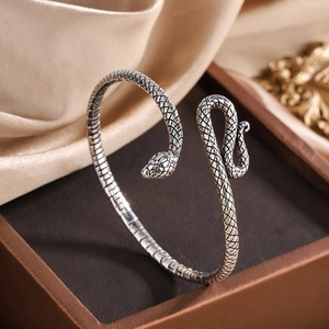 Vintage silver snake bangle with textured scales on a leather jewelry box display