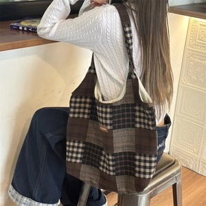 Borsa tote in tela a quadri marroni mostrata a spalla in un contesto di stile di vita